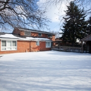 Red brick 2-story house is surrounded by a large snow covered fenced in backyard.